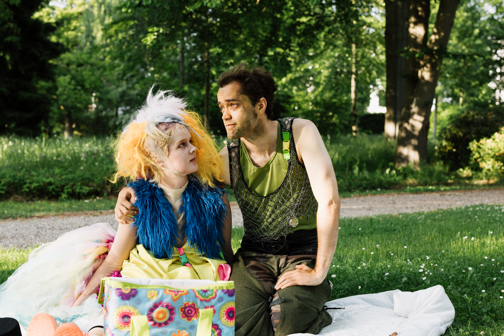 Soldat und Prinzessin sitzen auf einer Decke in einem Park, er legt seinen Arm um sie