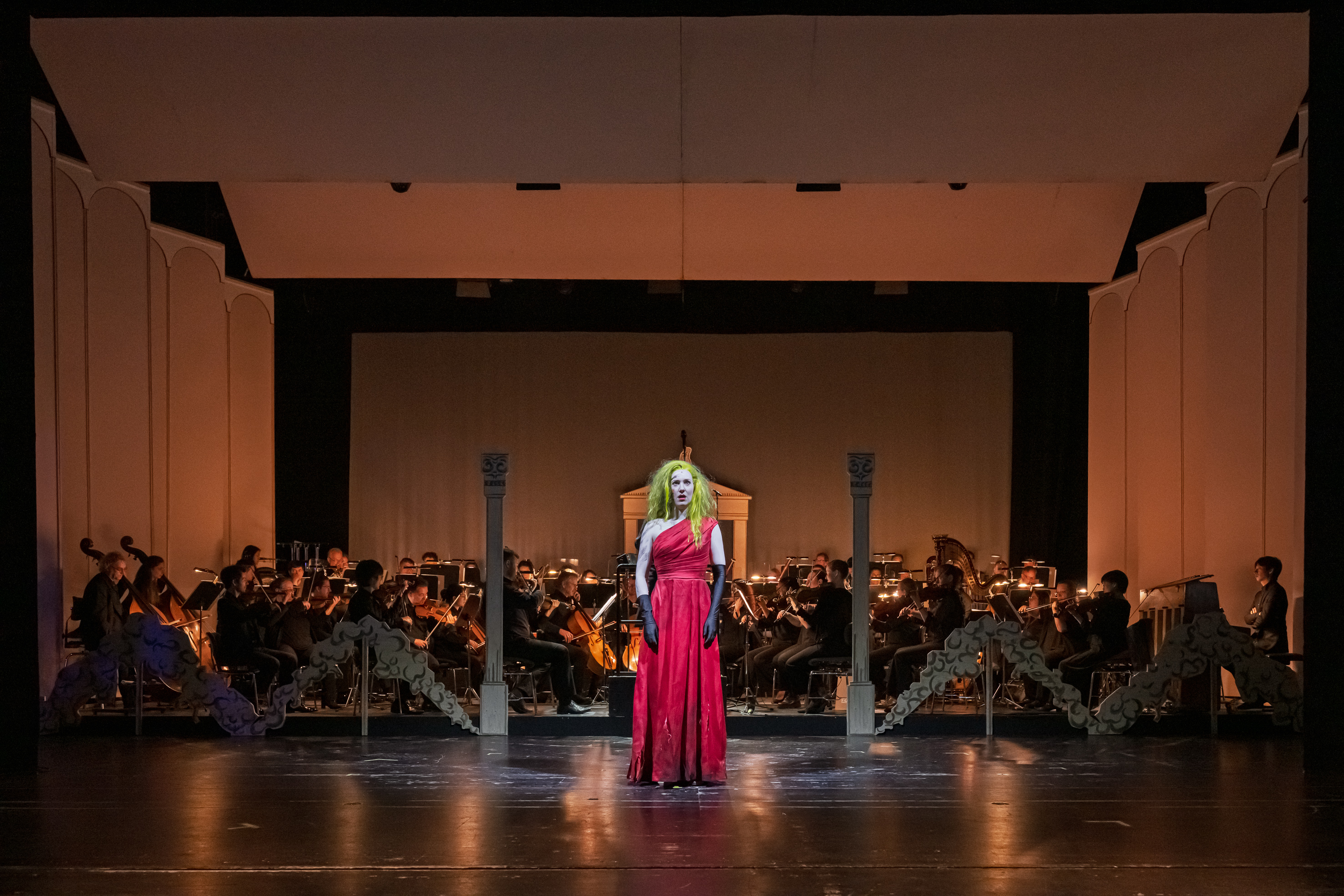 Frau in rotem Kleid auf der Bühne vor einem Orchester
